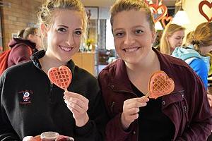 两个女生拿着心形华夫饼在宿舍庆祝情人节